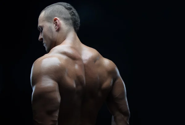 Bodybuilder en strip thema: mooi met naakte man gepompt spieren poseren in de studio op een donkere achtergrond — Stockfoto