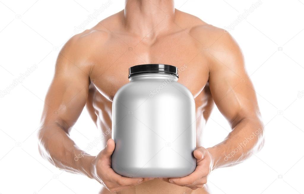 Bodybuilding and Sports theme: handsome strong bodybuilder holding a plastic jar with a dry protein and showing gesture isolated on white background in studio
