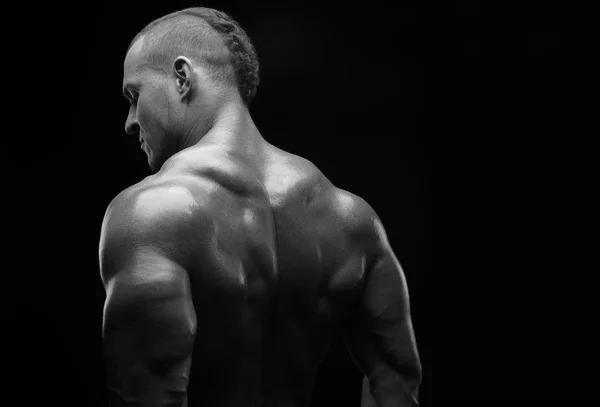 Bodybuilder et strip thème : belle avec des muscles pompés homme nu posant dans le studio sur un fond sombre, photo noir et blanc — Photo