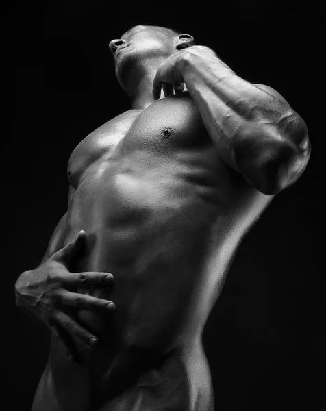 Culturista y tema de la tira: hermosa con músculos bombeados hombre desnudo posando en el estudio sobre un fondo oscuro, foto en blanco y negro — Foto de Stock