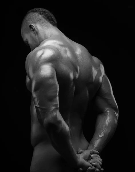 Bodybuilder und Strip-Thema: Schön mit gepumpten Muskeln, nackter Mann posiert im Studio vor dunklem Hintergrund, Schwarz-Weiß-Foto — Stockfoto