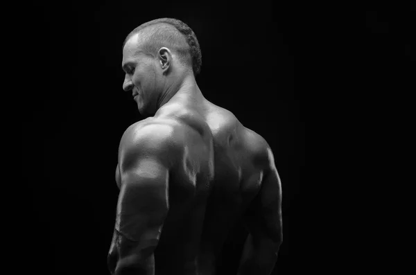 Bodybuilder und Strip-Thema: Schön mit gepumpten Muskeln, nackter Mann posiert im Studio vor dunklem Hintergrund, Schwarz-Weiß-Foto — Stockfoto