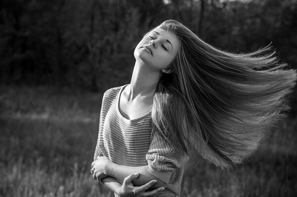 Dramatic portrait of a girl theme: portrait of a beautiful girl with flying hair in the wind against a background in the forest studio