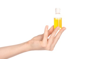 Beauty and health topic: a woman's hand holding a small yellow bottle of shampoo in the studio isolated on a white background