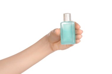 Beauty and health topic: a woman's hand holding a small green bottle of shampoo in the studio isolated on a white background
