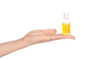 Beauty and health topic: a woman's hand holding a small yellow bottle of shampoo in the studio isolated on a white background