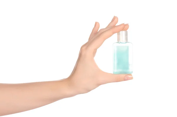 Beauty and health topic: a woman's hand holding a small green bottle of shampoo in the studio isolated on a white background