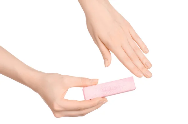 Argomento salute e cura delle mani: la mano di una donna tiene una lima per unghie per manicure isolata su sfondo bianco in studio — Foto Stock