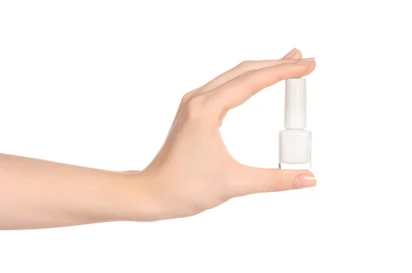 Manicura y belleza: la mano de una mujer sosteniendo una botella de esmalte de uñas blanco aislado sobre un fondo blanco en el estudio — Foto de Stock
