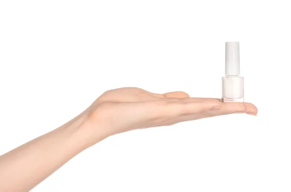 Manicura y belleza: la mano de una mujer sosteniendo una botella de esmalte de uñas blanco aislado sobre un fondo blanco en el estudio —  Fotos de Stock