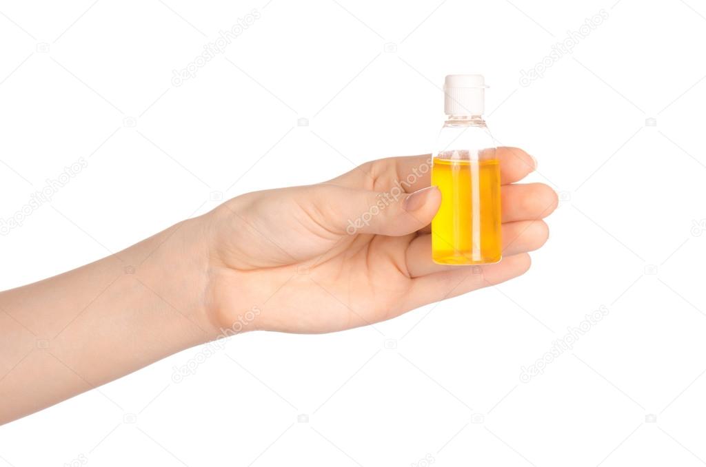 Beauty and health topic: a woman's hand holding a small yellow bottle of shampoo in the studio isolated on a white background