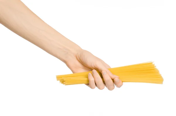 Thème Cuisine et Cuisine : main humaine tenant une pile de spaghettis jaunes secs isolés sur fond blanc en studio — Photo