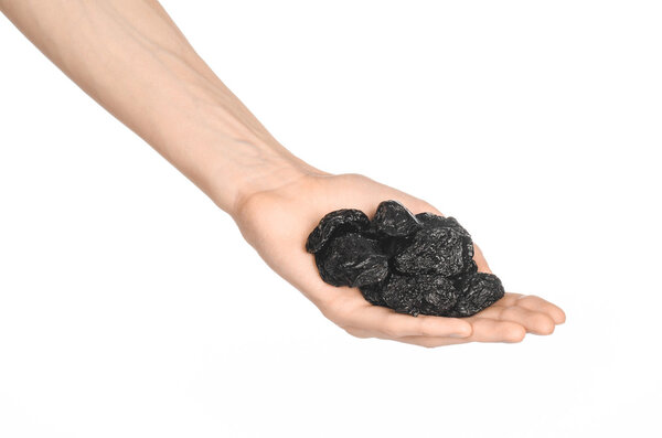 Dried fruits and cooking theme: man's hand holding a black Dried prunes isolated on a white background in studio