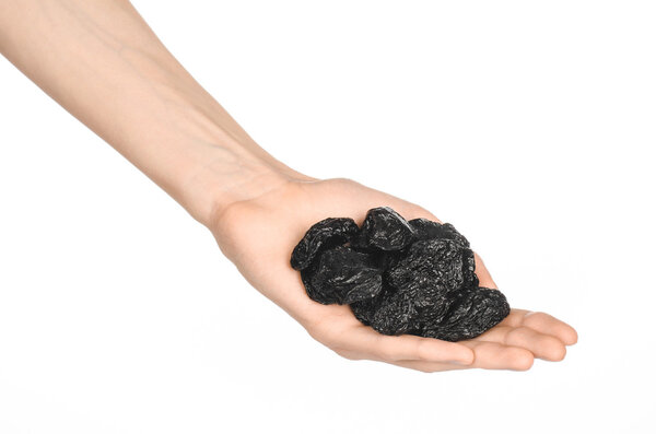 Dried fruits and cooking theme: man's hand holding a black Dried prunes isolated on a white background in studio