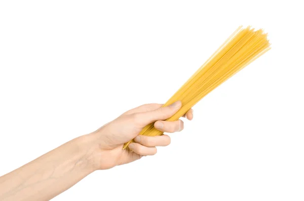 Kitchen and Cooking topic: human hand holding a pile of dry yellow spaghetti isolated on white background in studio — Stock fotografie