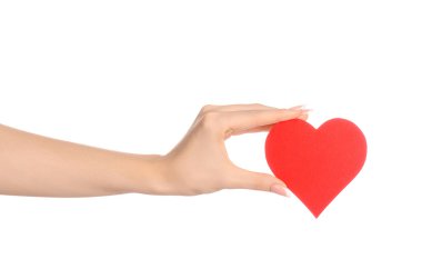 Love and greetings card theme: beautiful female hand holding a paper card red heart isolated on a white background in studio