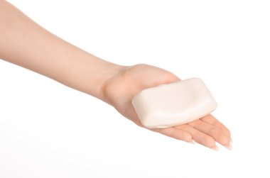 Hygiene and health care topic: a woman's hand holding a white bar of soap isolated on white background in studio
