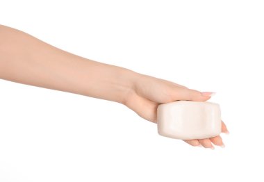 Hygiene and health care topic: a woman's hand holding a white bar of soap isolated on white background in studio