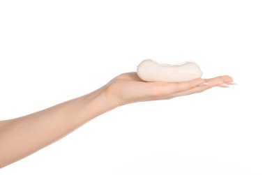 Hygiene and health care topic: a woman's hand holding a white bar of soap isolated on white background in studio
