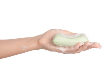 Hygiene and health care topic: a woman's hand holding a green bar of soap isolated on white background in studio