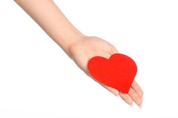Love and greetings card theme: beautiful female hand holding a paper card red heart isolated on a white background in studio — Stok fotoğraf