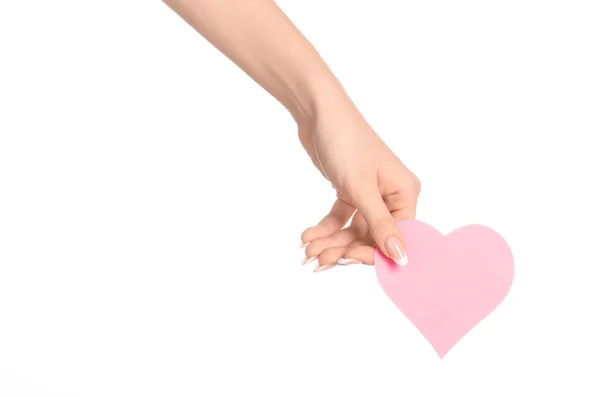 Love and greetings card theme: beautiful female hand holding a paper card pink heart isolated on white background in studio — Stock Photo, Image