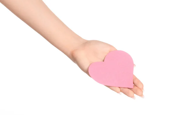 Love and greetings card theme: beautiful female hand holding a paper card pink heart isolated on white background in studio — Stok fotoğraf
