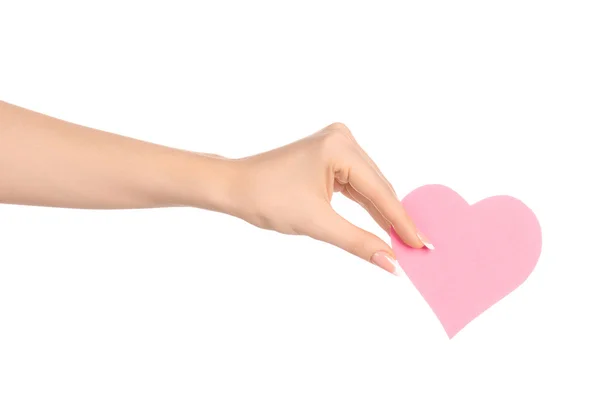 Tema de la tarjeta de amor y saludos: hermosa mano femenina sosteniendo una tarjeta de papel corazón rosa aislado sobre fondo blanco en el estudio — Foto de Stock