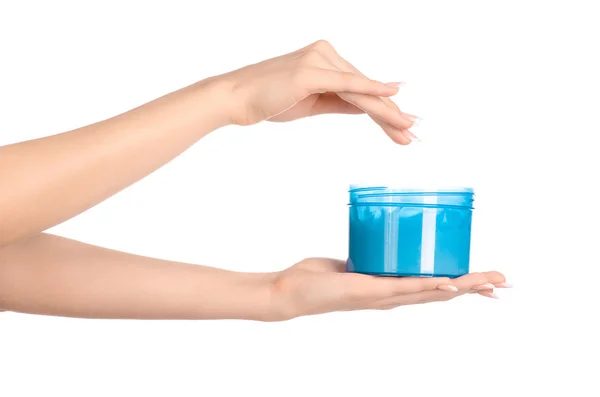Thema Gesundheit und Körperpflege: Die Hand einer Frau hält ein blaues Glas mit Creme auf weißem Hintergrund — Stockfoto