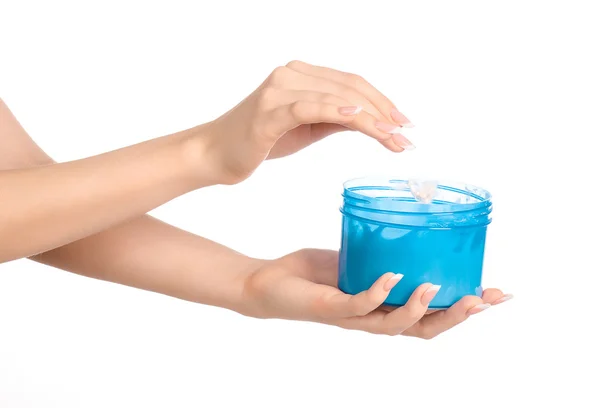 Tema salute e cura del corpo: una mano di donna che tiene un barattolo blu con crema isolata su sfondo bianco — Foto Stock