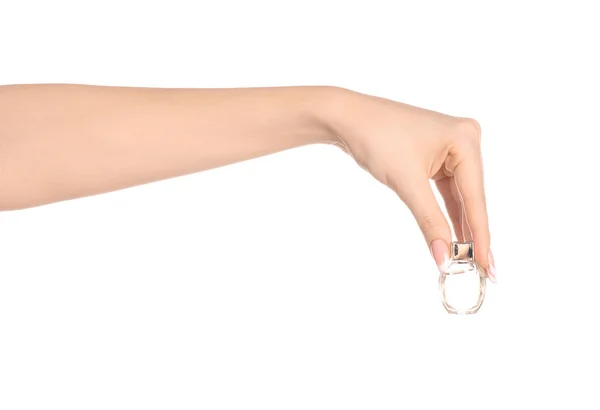 Perfume and body care theme: beautiful female hand holding a small transparent bottle of perfume on a white background isolated — Stok fotoğraf
