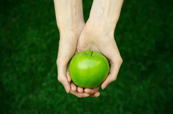 Vegetarianos y frutas y verduras frescas sobre la naturaleza del tema: mano humana sosteniendo una manzana verde sobre un fondo de hierba verde vista superior —  Fotos de Stock