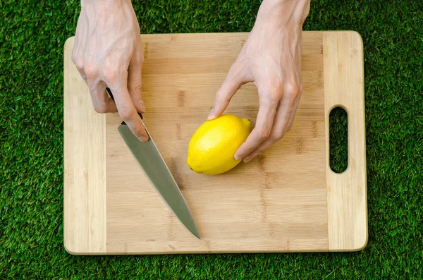 Vegetariani e cucina sulla natura del tema: sdraiato su un tagliere e coltello giallo limone sullo sfondo di erba — Foto Stock