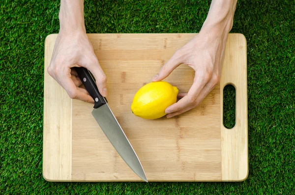 Vegetariani e cucina sulla natura del tema: sdraiato su un tagliere e coltello giallo limone sullo sfondo di erba — Foto Stock