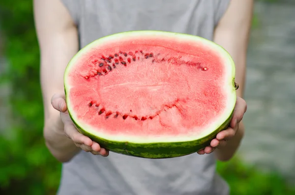 Summer and fresh watermelon theme: a man holds a watermelon on the green background — Stock Photo, Image