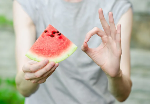 Summer and fresh watermelon theme: a man holds a slice of watermelon on a green background — Stock Photo, Image