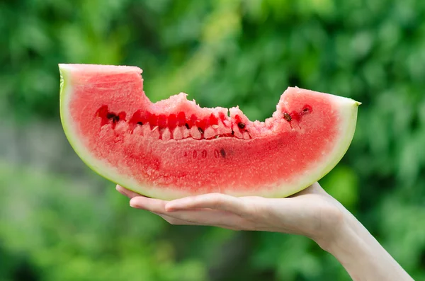 Summer and fresh watermelon theme: a man holds a slice of watermelon on a green background — Stock Photo, Image