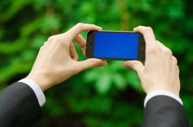 İletişim ve iş Konu: siyah elbiseli mavi ekran ile modern bir telefon yeşil çim arka planda tutan bir el