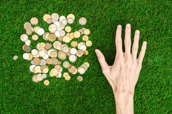 Money and Finance Topic: Money coins and human hand showing gesture on a background of green grass top view