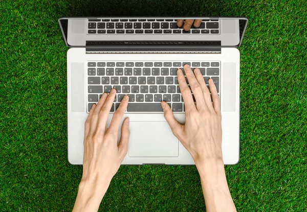 Work outdoors theme: the human hand shows gestures and an open notebook on a background of green grass top view