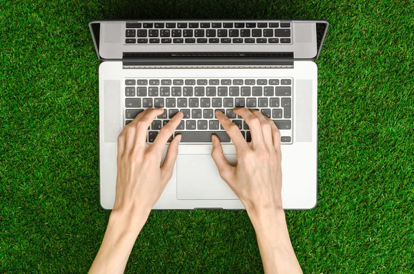 Work outdoors theme: the human hand shows gestures and an open notebook on a background of green grass top view