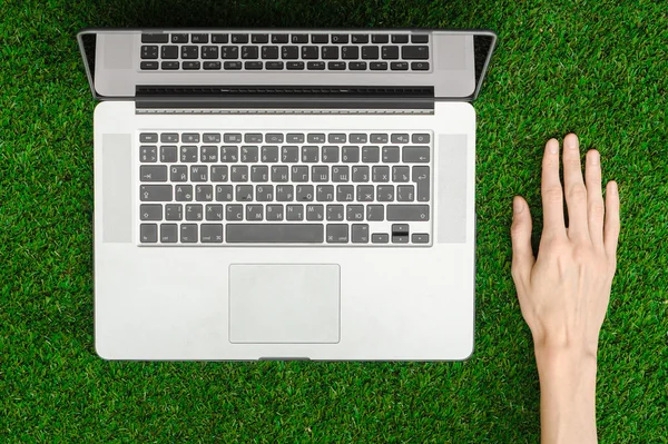 Work outdoors theme: the human hand shows gestures and an open notebook on a background of green grass top view