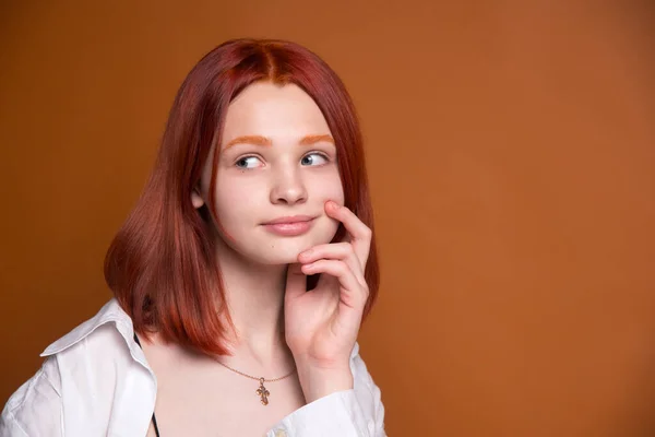 茶色のモノクロームの背景に赤い髪の女の子 大きな肖像画 サイドへの驚きの表情 — ストック写真