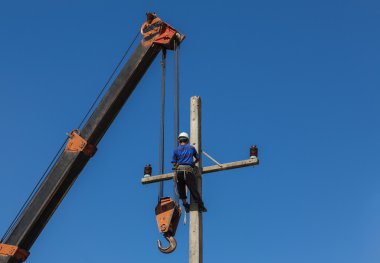Tırmanma elektrikçi elektrik kolon üzerinde vinç ile çalışıyor.