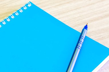 Pen blue and Blank blue book boş cover book spiral kırtasiye okulu malzemeleri eğitim işi fikri kitabı kapak tasarımı not defteri notları ahşap arkaplan.