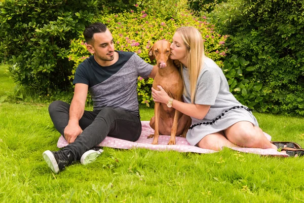 Couple on rug with woman kissing dog — Stock Photo, Image