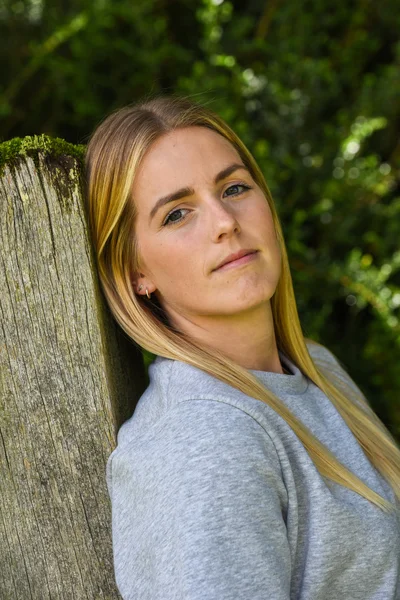 Close-up of blonde leaning against wooden gatepost — Stock Photo, Image