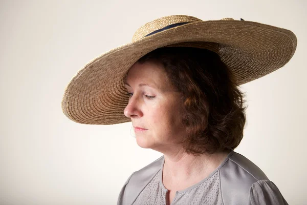 Brunette in wide-brimmed straw hat looking down — Stock Photo, Image