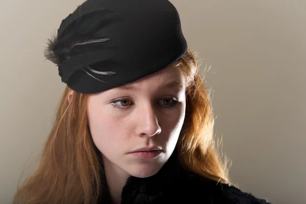 Närbild av redhead i svart befjädrade hatt — Stockfoto