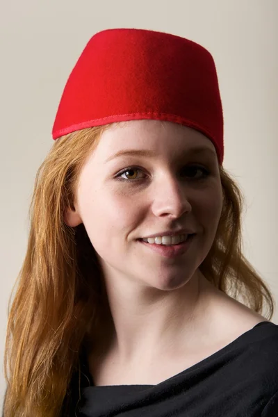 Smiling redhead in red felt Moroccan fez — Stock Photo, Image